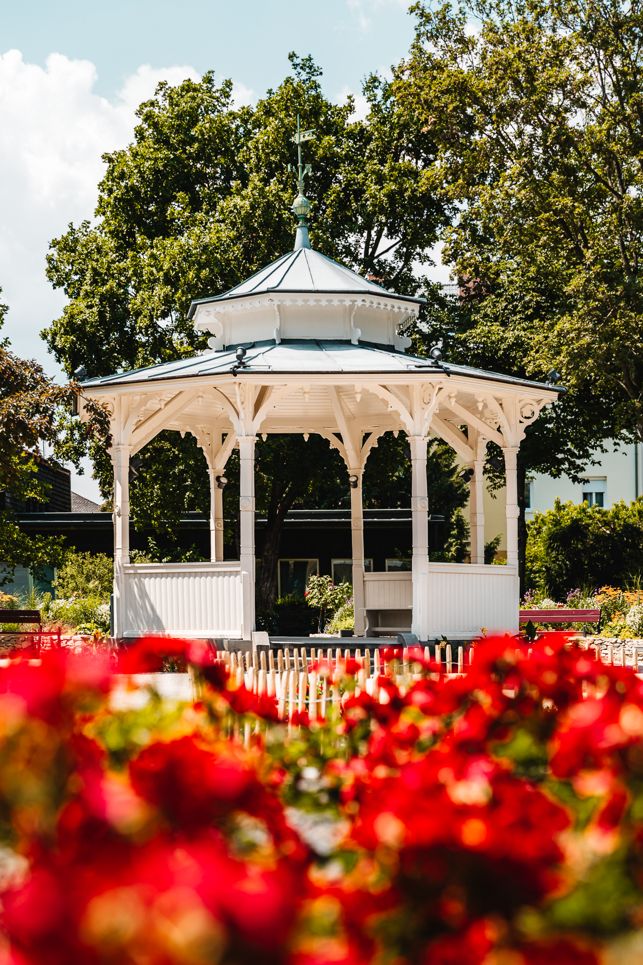 White pavilion in front of blooming red flowers