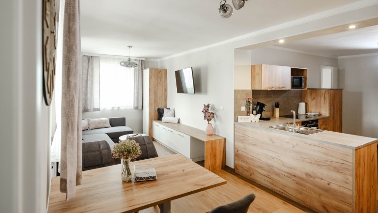 Modern eat-in kitchen with wooden furniture and gray sofa.