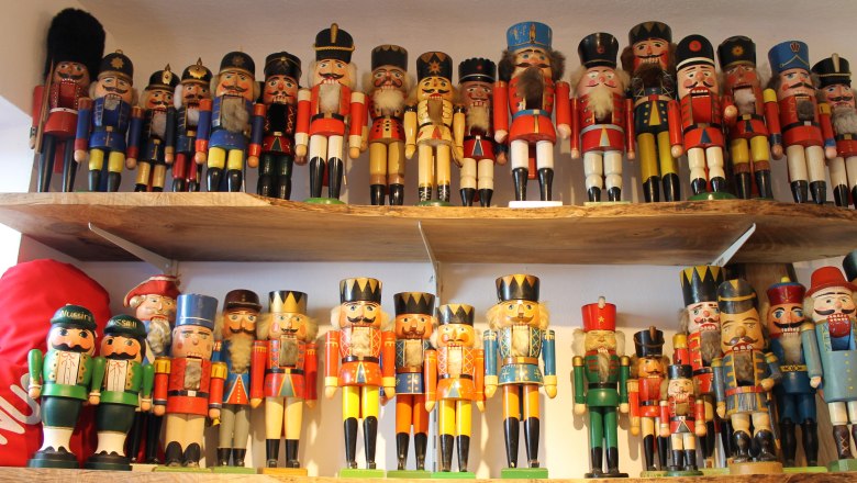 A collection of colorful nutcracker figures on two wooden shelves.