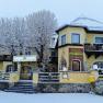A yellow hotel with the name Kaiser Franz Josef in winter, surrounded by snow-covered trees and a snowy forecourt.
