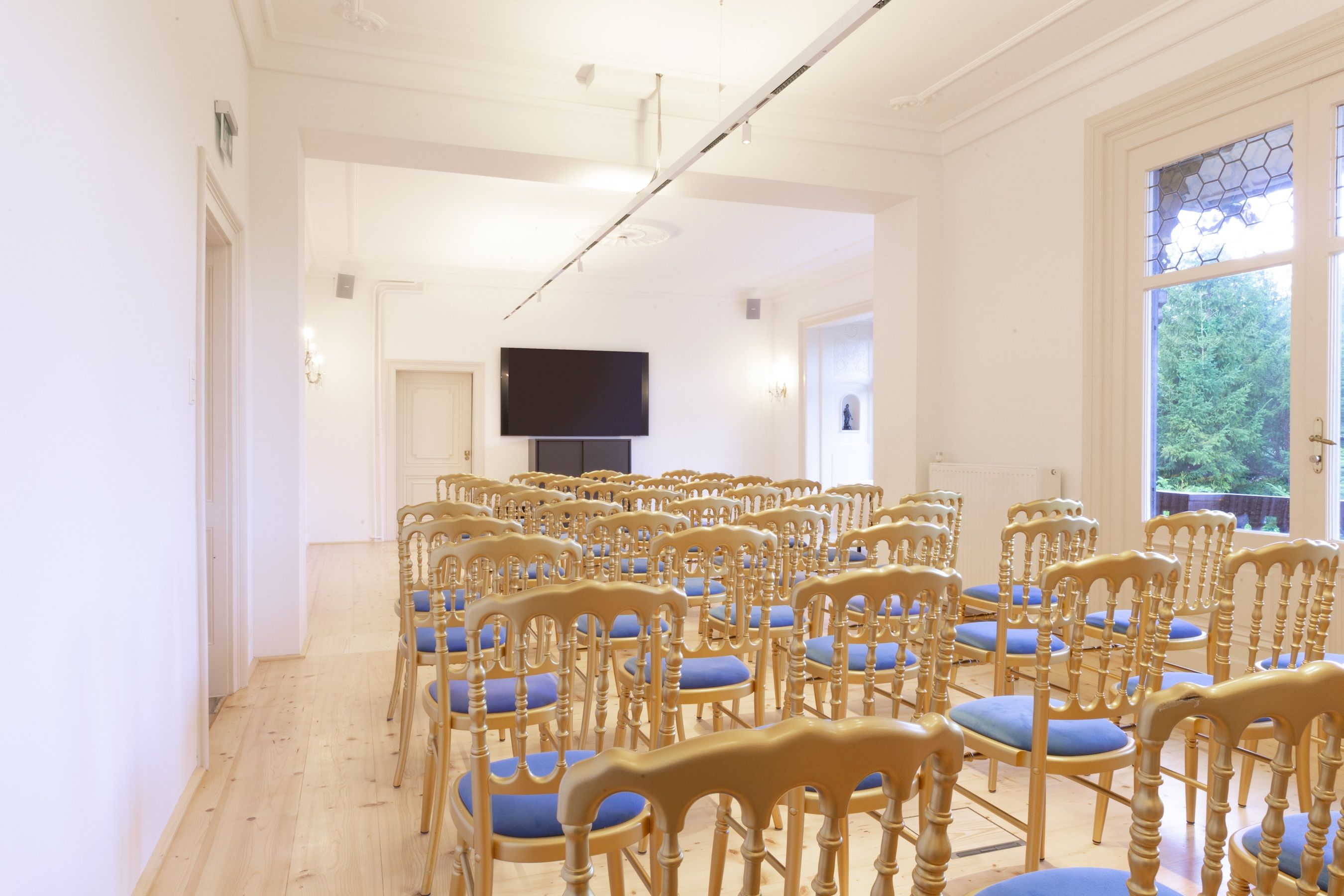 A bright lounge with rows of chairs and a large screen on the wall.