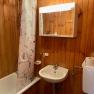 Wood-paneled bathroom with bathtub, shower curtain, washbasin and mirror cabinet.