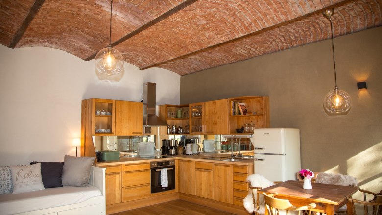 Cozy kitchen with wooden furniture, tiled ceiling and dining table.