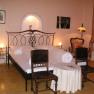 Cozy bedroom with double bed, antique chairs and table lamp.