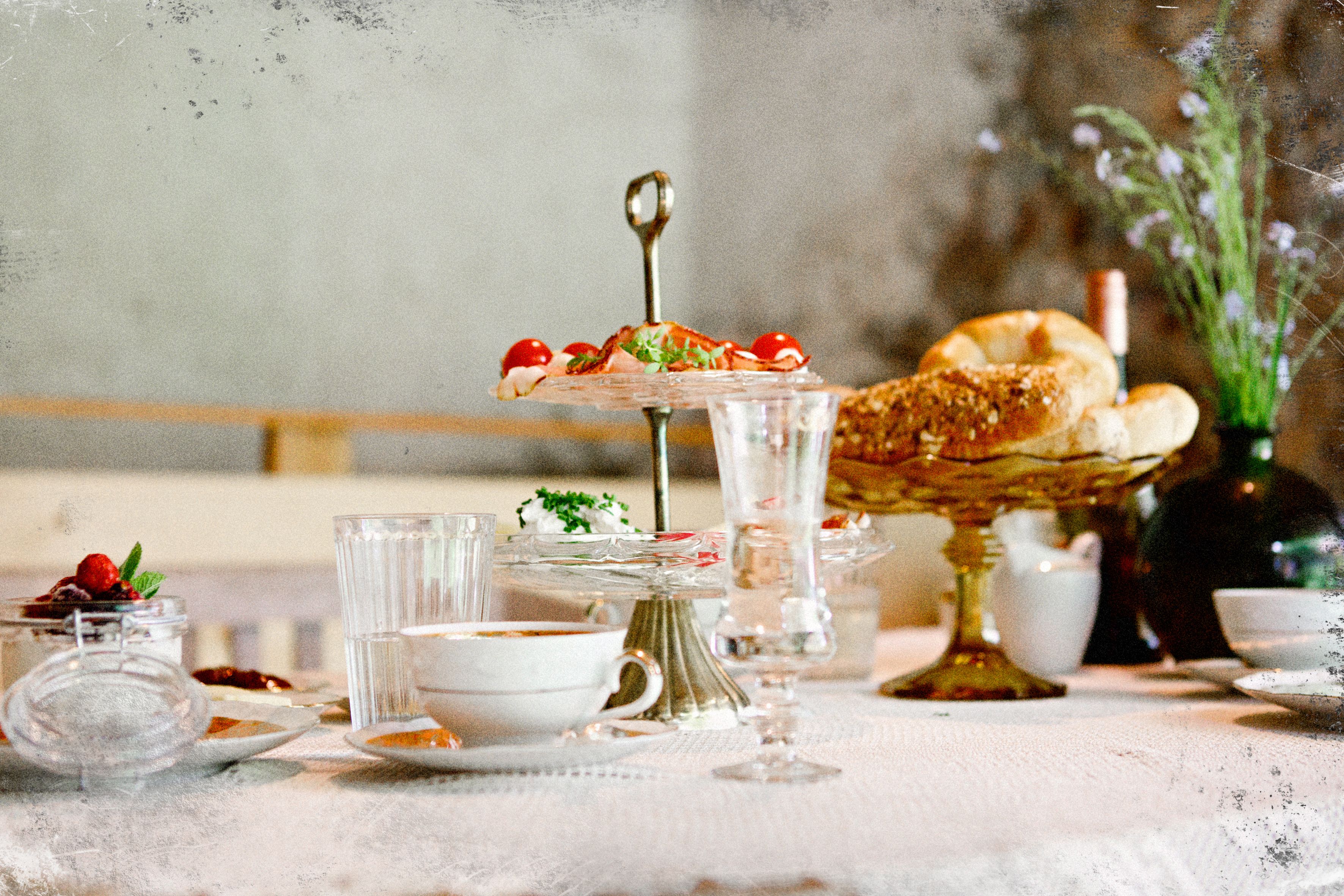 An elegantly set breakfast table with pastries, cold cuts, and beverages arranged on a tiered stand.