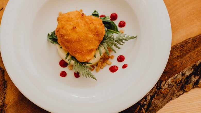 A baked egg on a plate with puree and red polka dots.