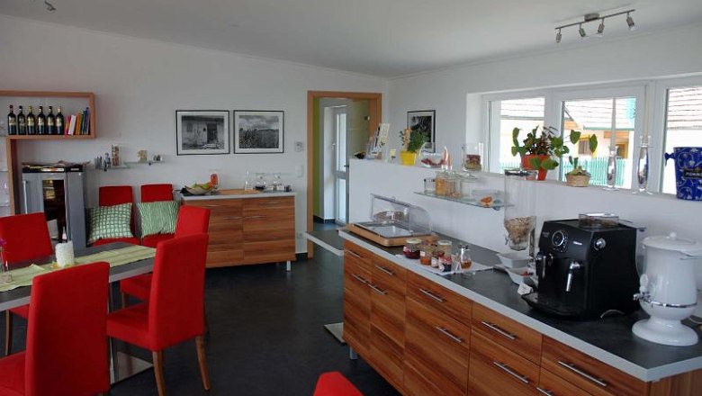 Breakfast room with red chairs, wooden furniture and coffee machine.