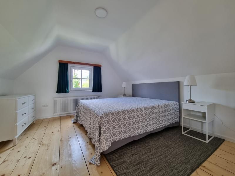 Bedroom with double bed, bedside tables and chest of drawers.
