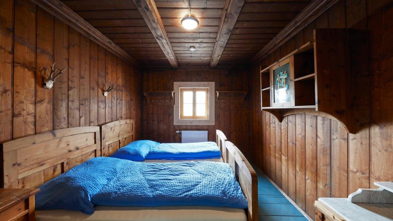 Rustic bedroom with wood paneling and double bed.