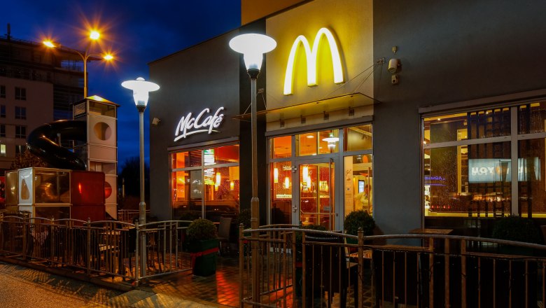 Exterior view of a McDonald's restaurant at night with illuminated logo and McCafé sign.