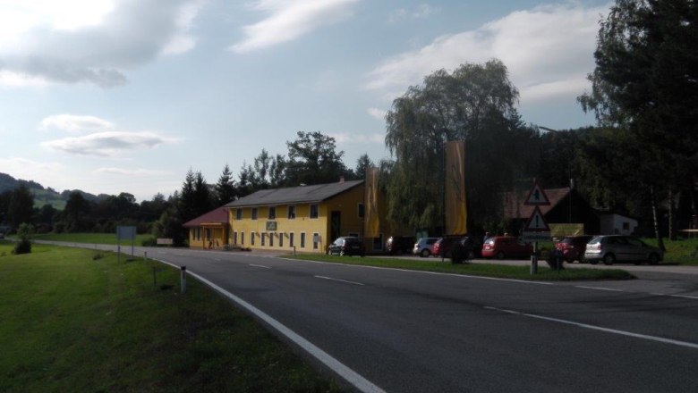 Country inn Schüller, © Landgasthof Schüller A yellow building on a country road with parked cars and trees in the background.