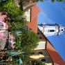 A flowering garden with pink chairs and tables in front of a historic building with a blue tower.