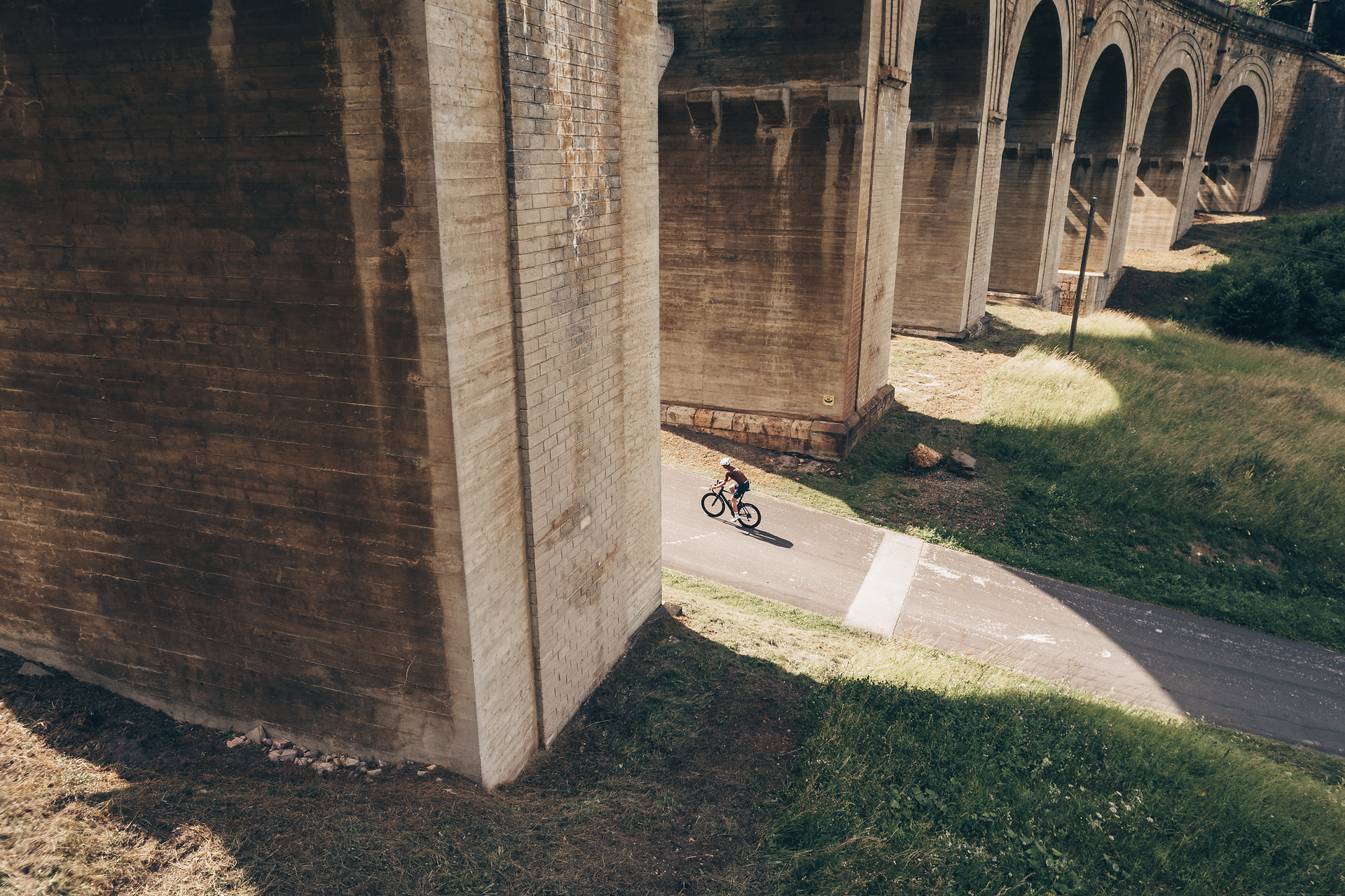 A cyclist glides relaxed along a narrow path, surrounded by the majestic backdrop of the Vienna Alps. The gentle hills and impressive bridges create a harmonious connection between nature and architecture that invites you to linger.
