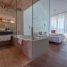 Modern hotel room with glass wall between bathroom and sleeping area.