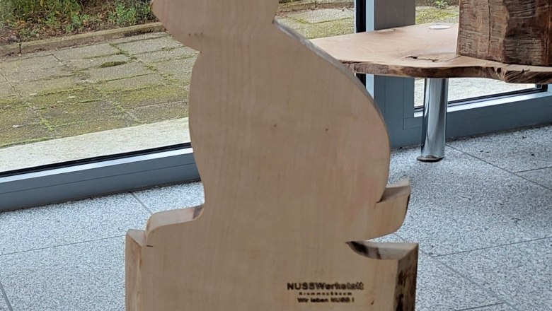 Wooden figure of a hare in front of a window with a view of a garden.