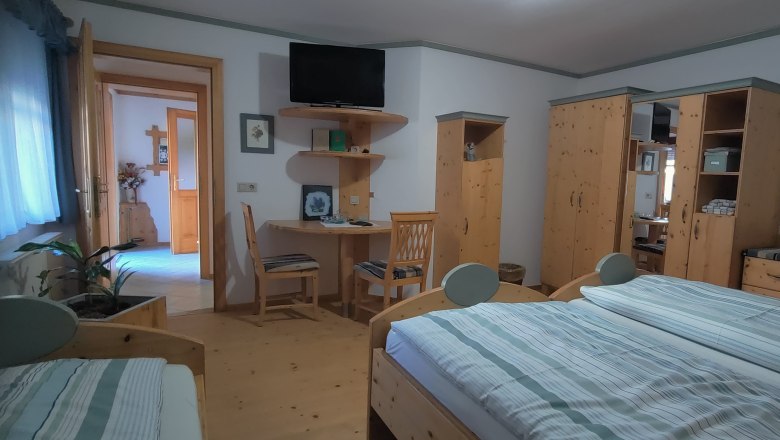 Comfortable bedroom with wooden furniture, double bed, desk and TV.