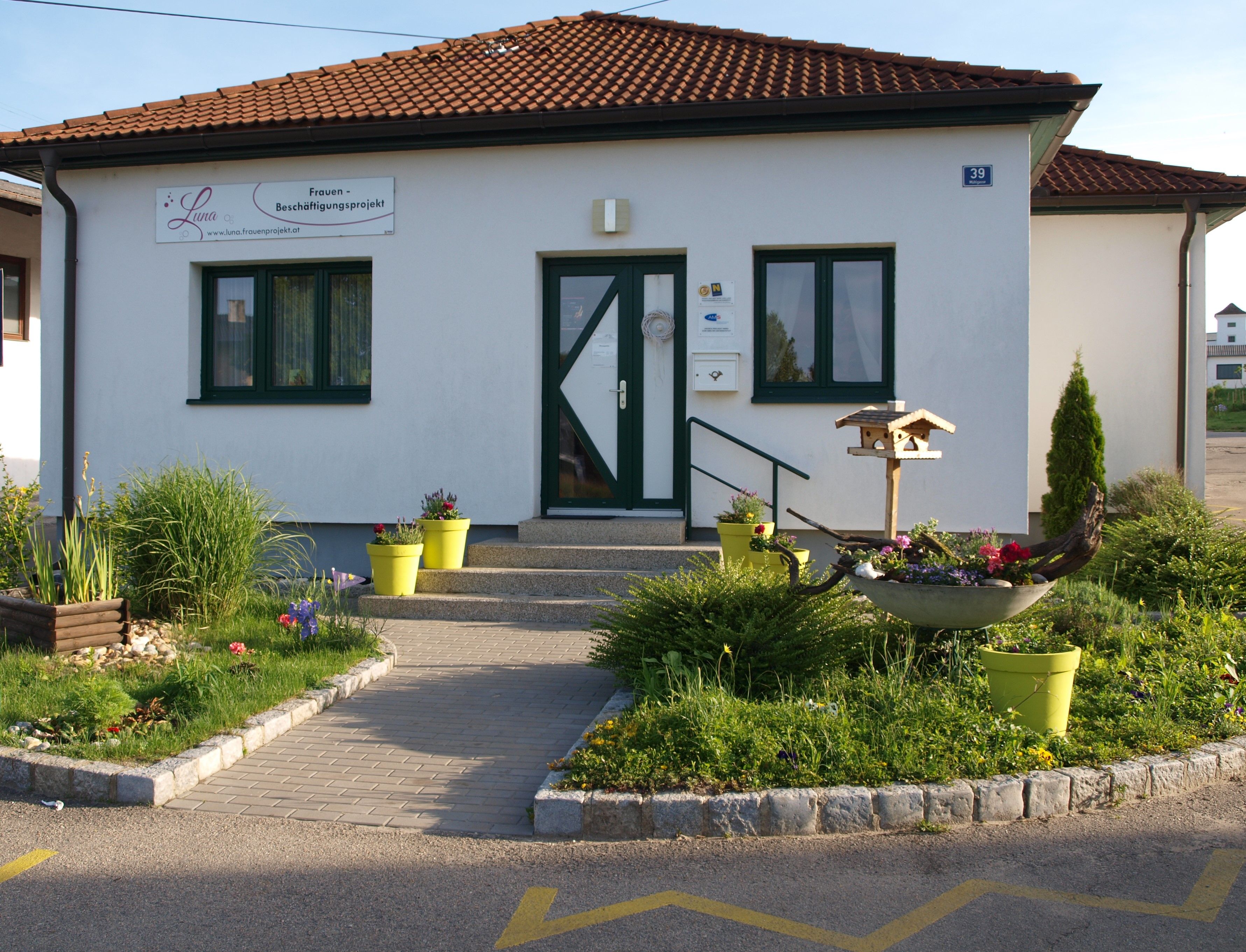 Entrance to a small building with garden and birdhouse.