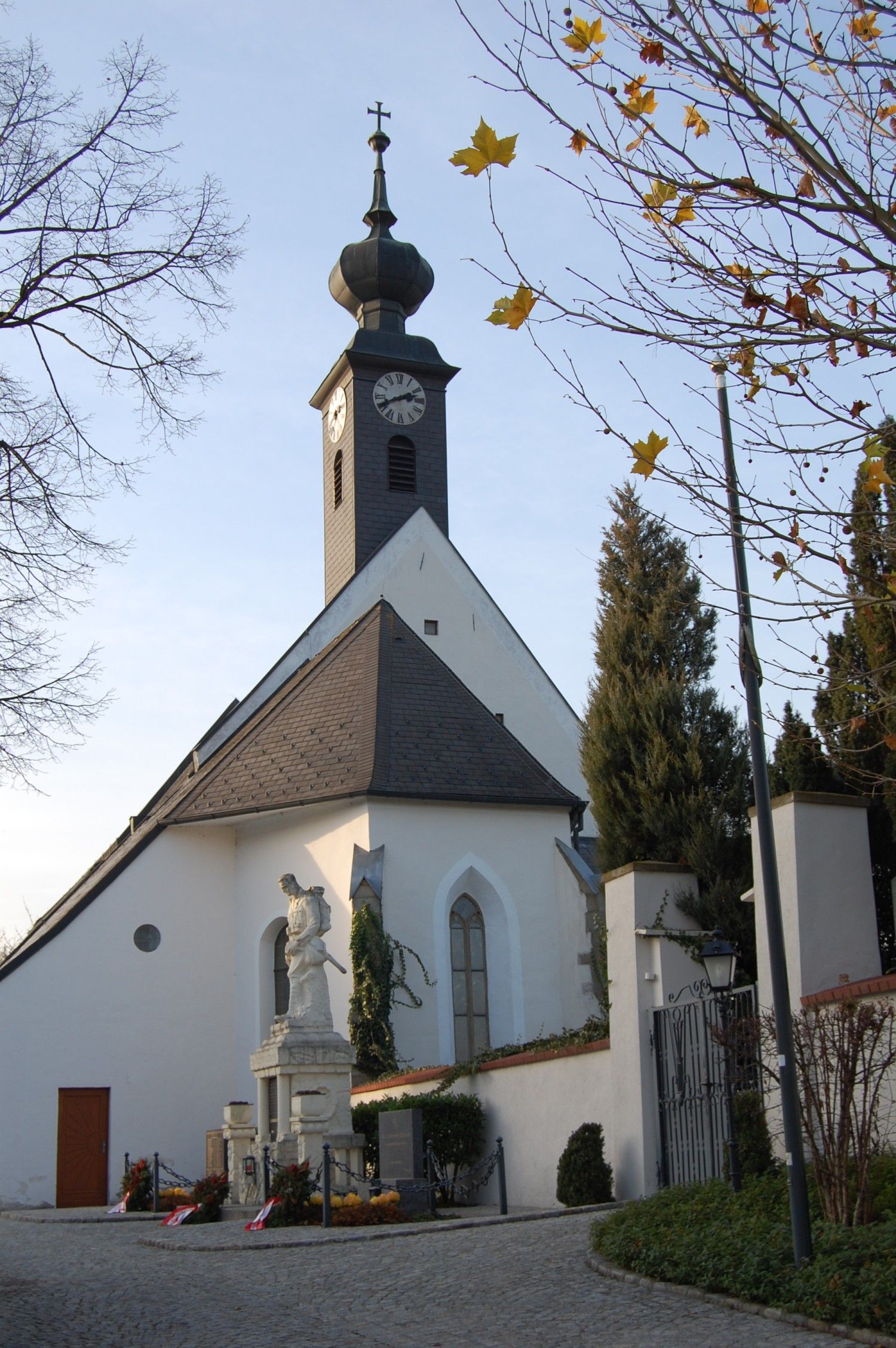 Gothic church in Kirchstetten with tower and statue in the foreground.