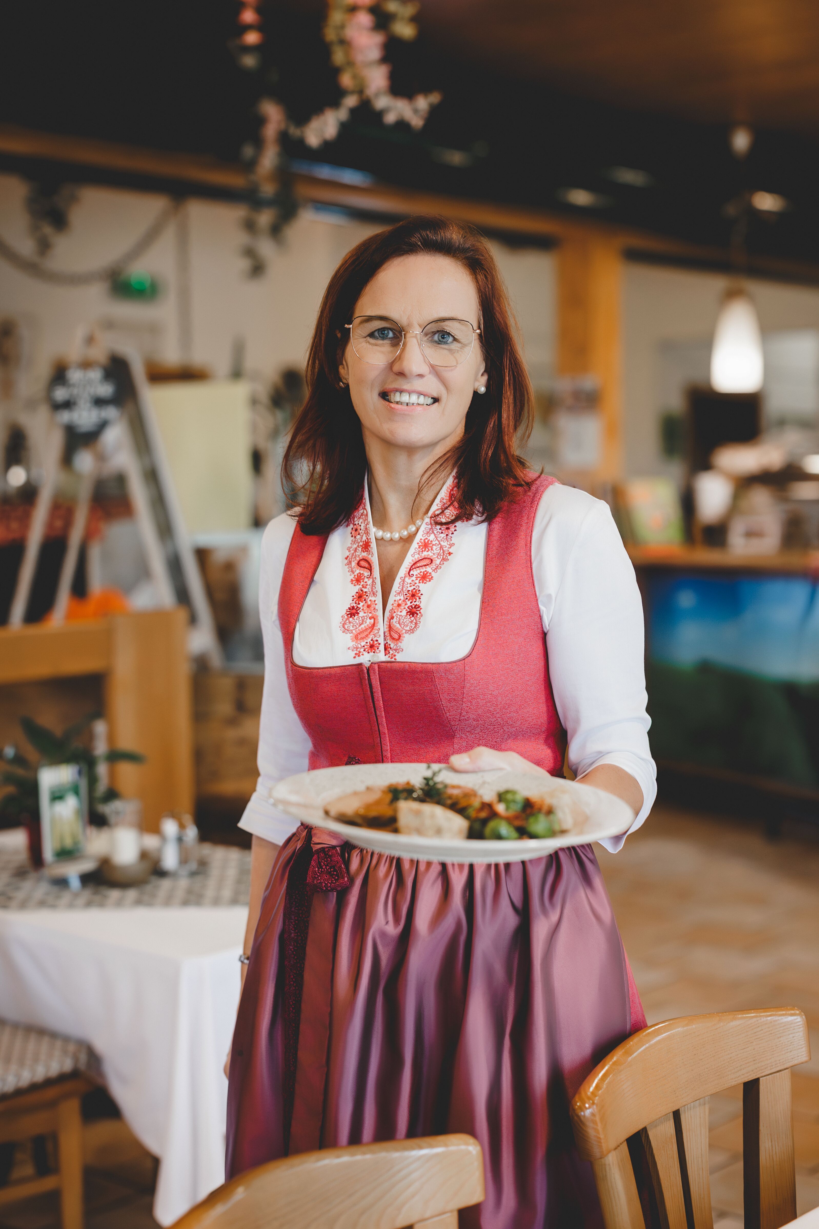 Woman in traditional costume serving a dish in a restaurant.