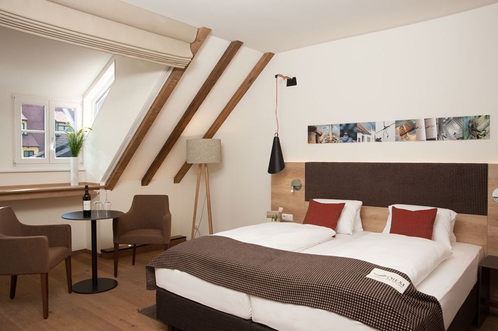 Comfortable hotel room with double bed, seating area and sloping roof.