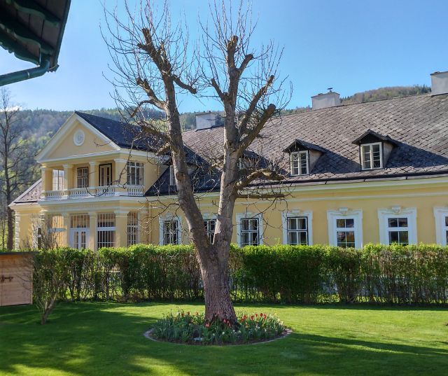 Yellow building with balcony and garden in the foreground.