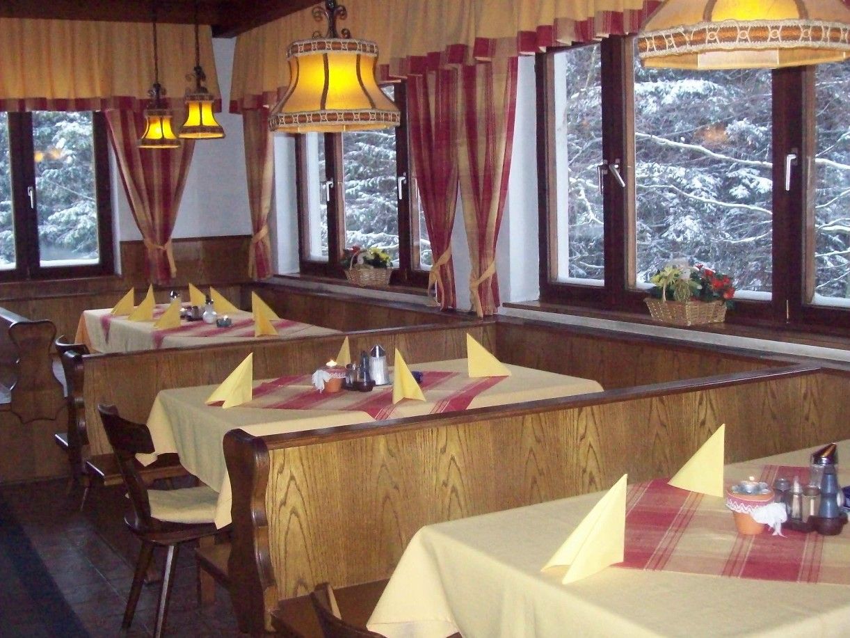 Interior view of a cozy inn with wooden furniture and laid tables.
