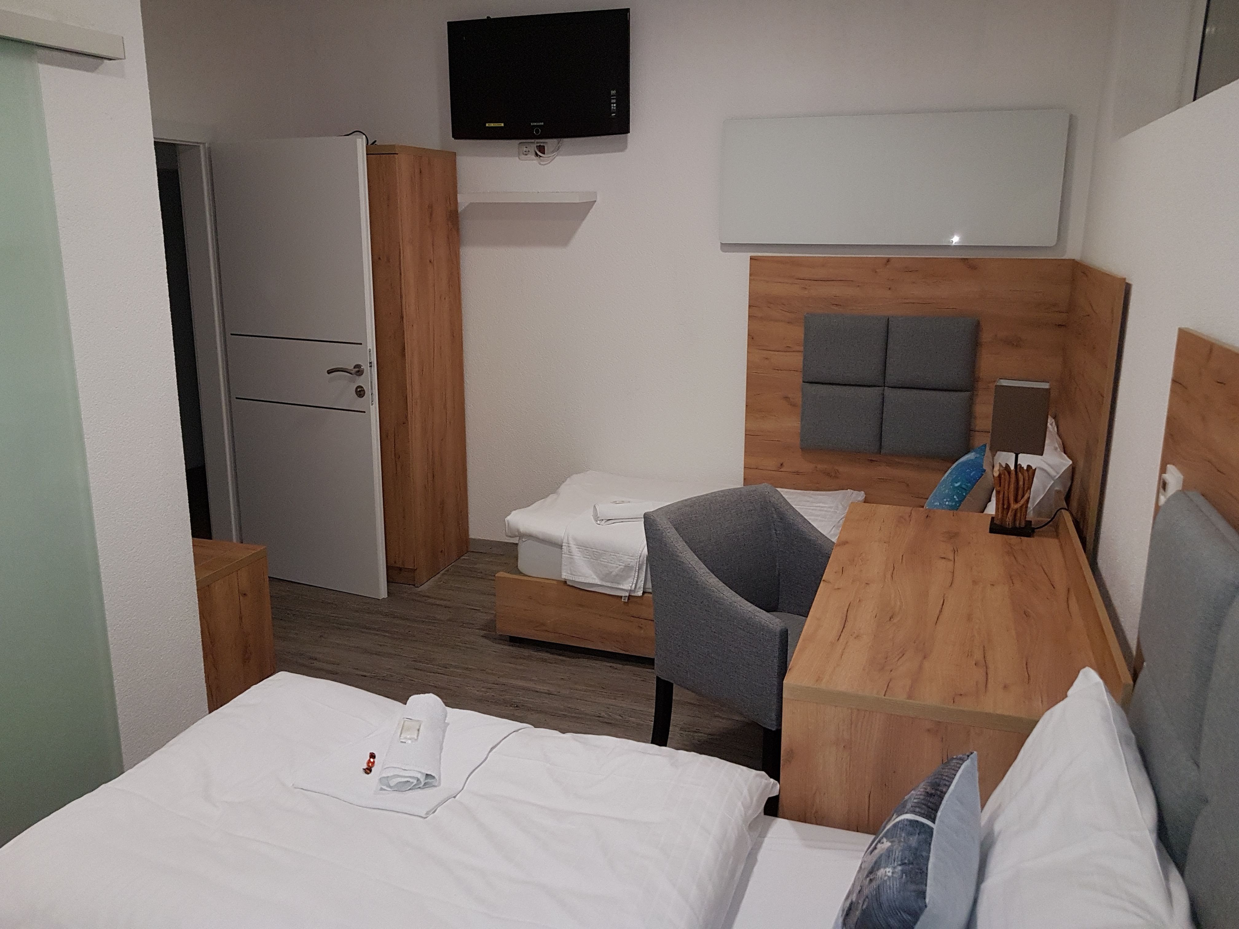 Hotel room with wooden furniture, two beds, a desk and a TV on the wall.
