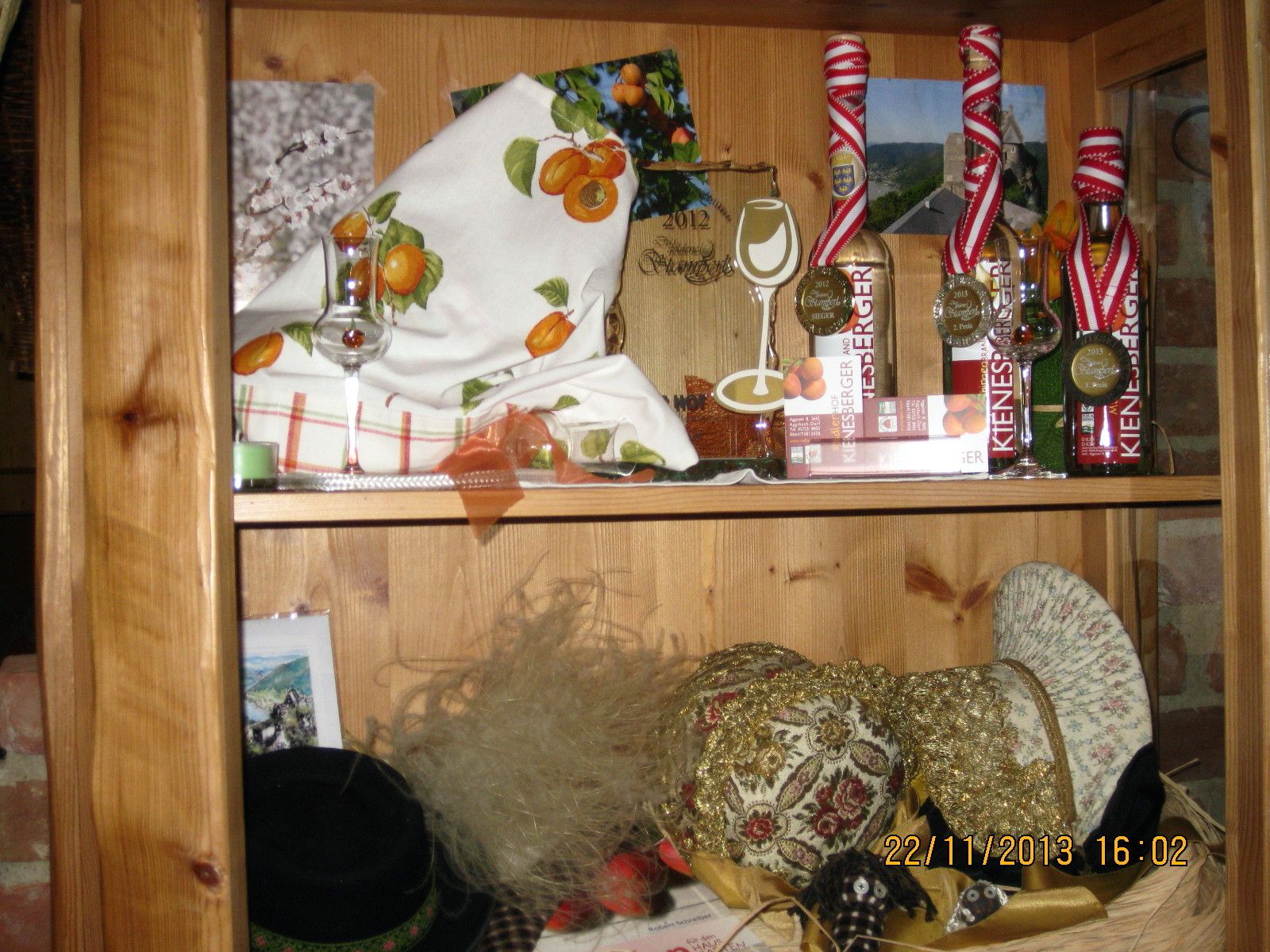 Wooden shelf with decorations, liqueur bottles and hats.