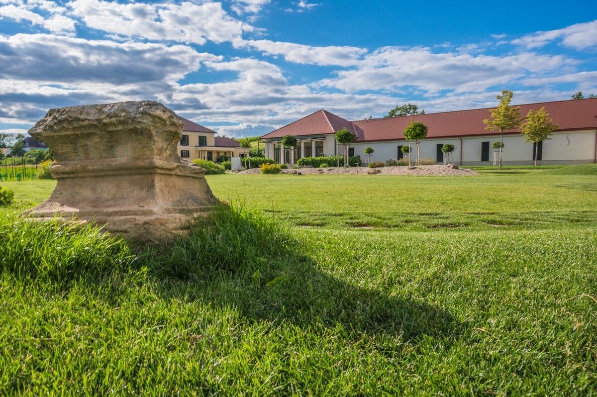 Winery with lawn and antique stone in the foreground.