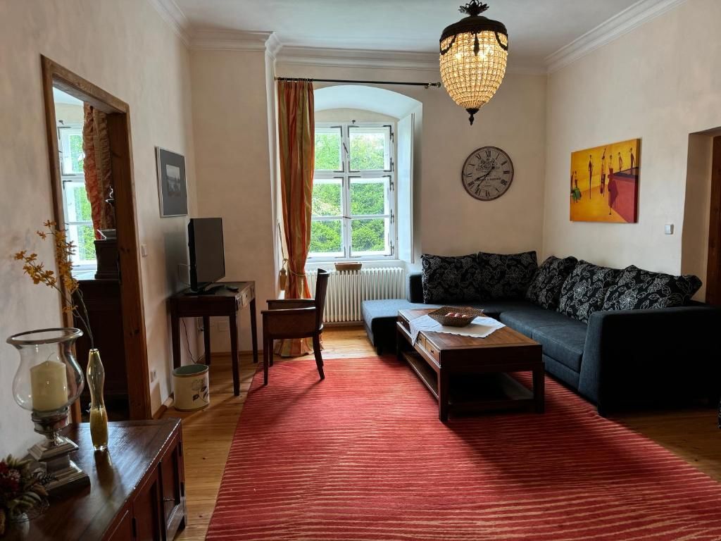 Cozy living room with sofa, red carpet, chandelier and large window.