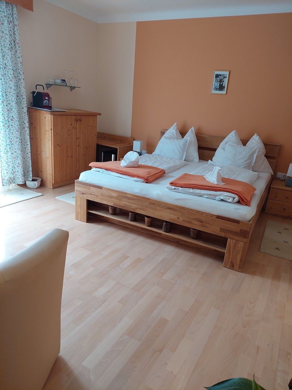 Cozy bedroom with double bed, wooden furniture and orange wall.
