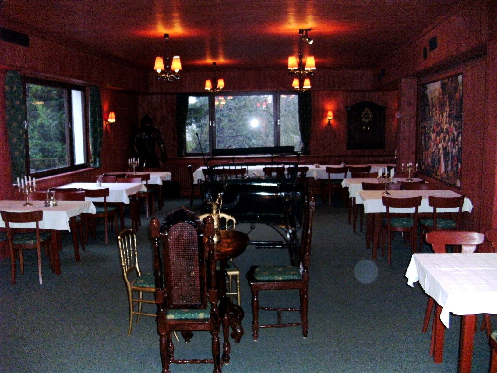 A rustic ballroom with wooden walls, laid tables and a piano in the background.