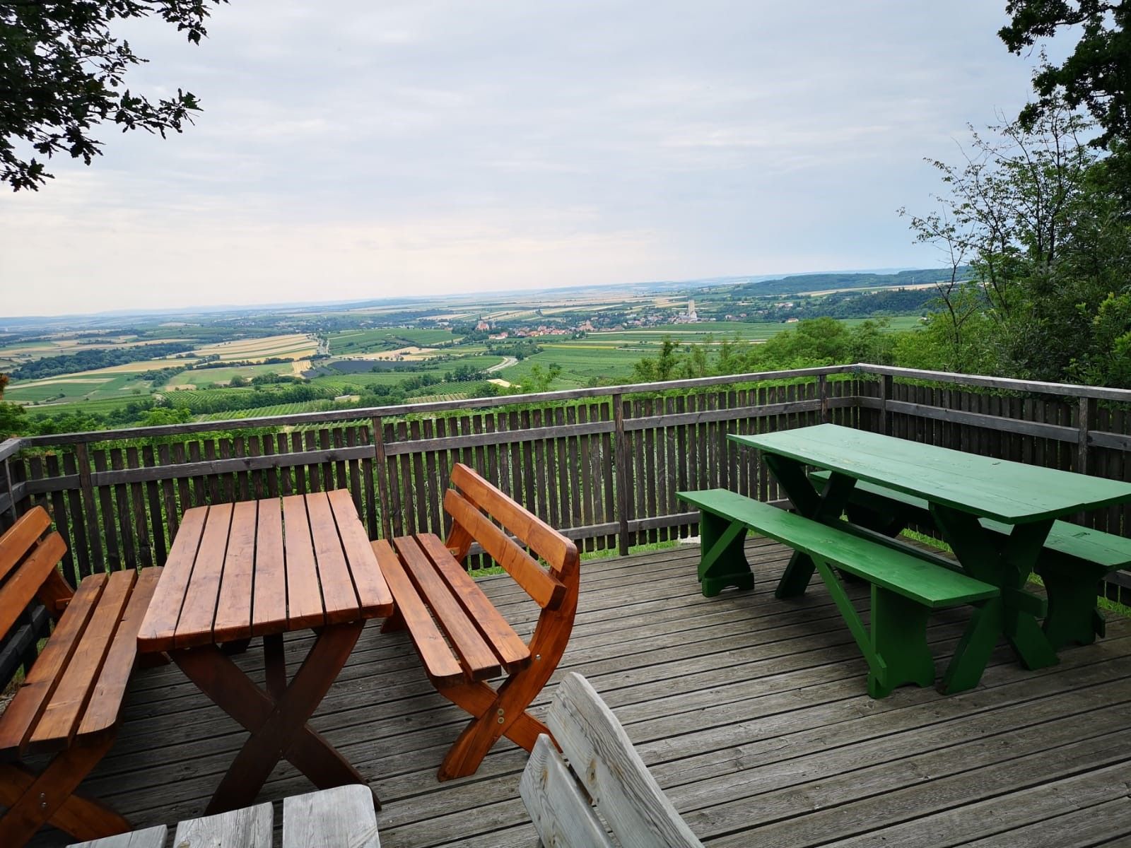 Viewing platform with wooden benches and tables, view of the wide landscape and fields.