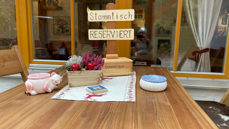 A rustic table with a 'Stammtisch Reserviert' sign, decorations and an ashtray.