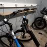 Three e-bikes in a garage being charged at a power strip.