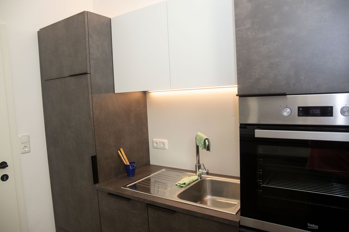 Modern kitchen with sink, oven and cupboards.
