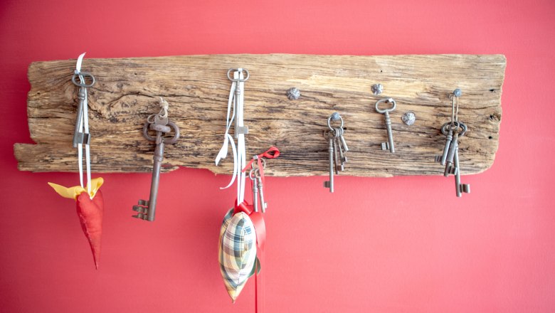 Vacation apartment Mistelbach, © Michael Sokolar Old keys hang on a rustic wooden board in front of a red wall.