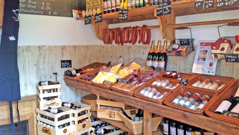 Interior view of a farm store with shelves full of regional products such as wine, sausage, spices and oil.