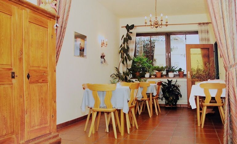 A cozy dining room with wooden furniture, plants and a chandelier.