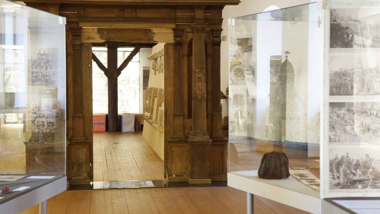 Interior view of a museum with wooden doors and display cases.