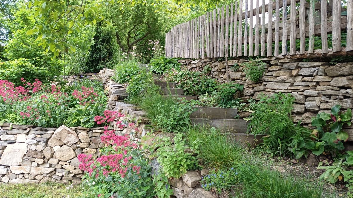 Stone steps in the garden with flowers and wooden railings.