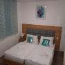 Double room with two single beds, wooden headboard, decorative cushions and a picture on the wall.