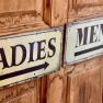 Signs for ladies' and men's toilets on wooden doors.