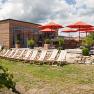 Terrace with sun loungers and red parasols in the garden.