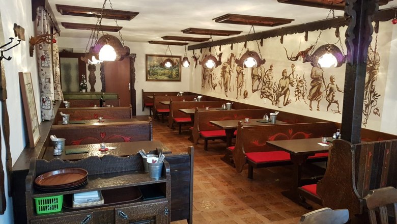 Interior view of a traditional Buschenschank (typical tavern) with wooden furniture and wall paintings.