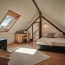 Cozy attic room with bed, desk and skylight.