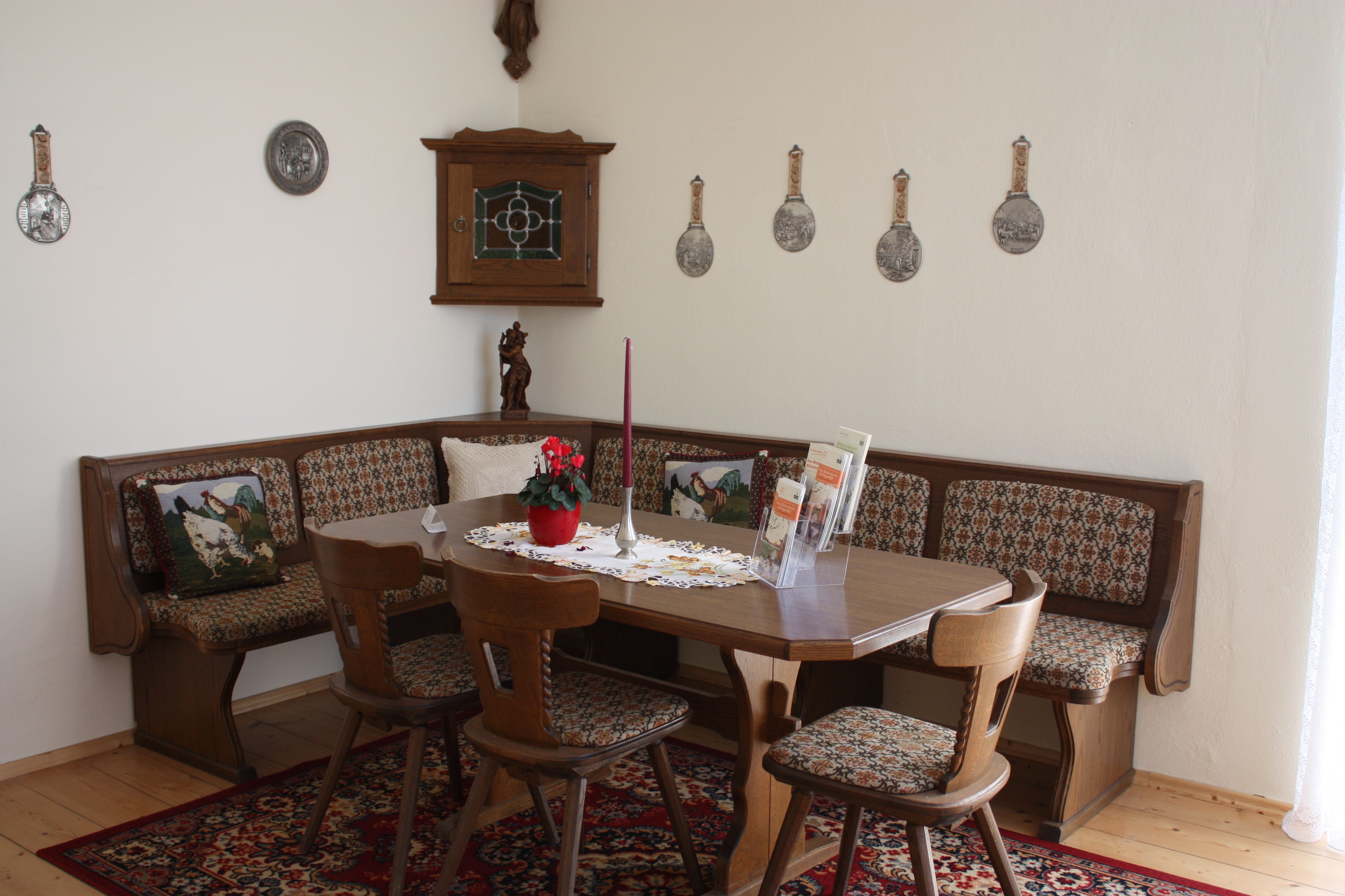 Traditional dining room with wooden furniture, corner bench and decorative wall plates.
