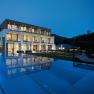 Modern boutique hotel with illuminated pool at night.