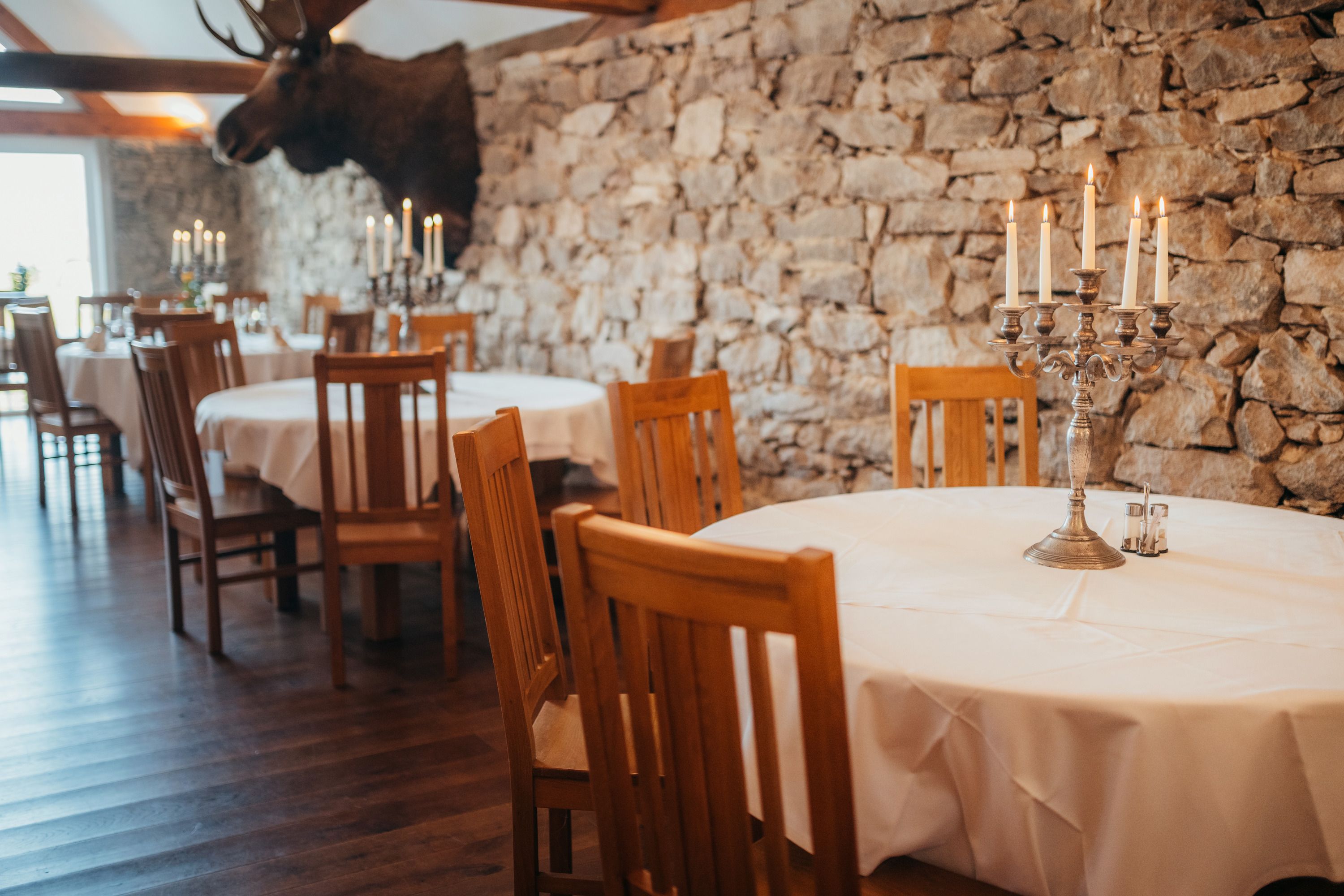 Rustic restaurant with stone wall, wooden furniture and candlesticks.