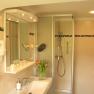 Modern bathroom with shower, washbasin, mirror and tulips.